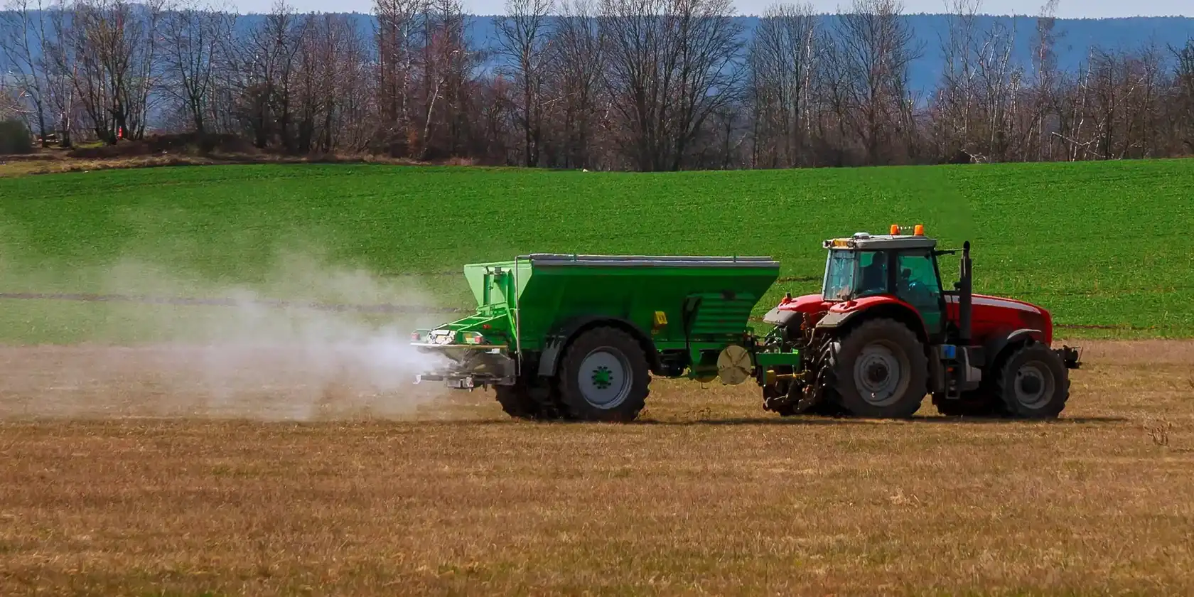 Równomierny wysiew granulatu Bluebird Fertilizers Ciągnik z rozsiewaczem podczas równomiernego wysiewu granulowanego nawozu Bluebird Fertilizers na polu